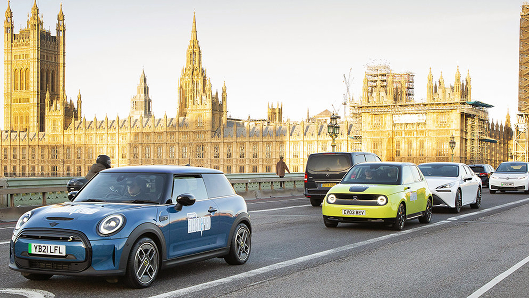 Electric cars drive past the Houses of Parliament on Westminster Bridge