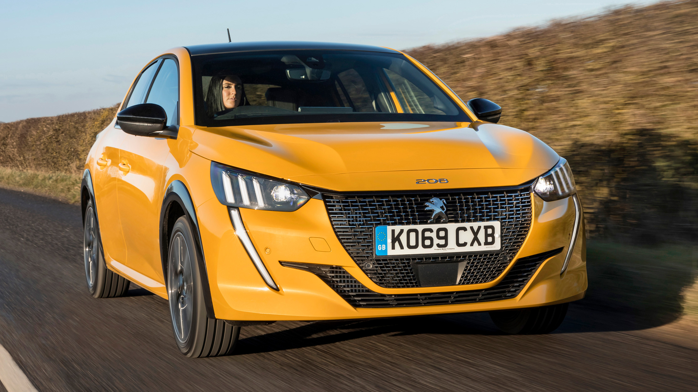 Driving shot of yellow Peugeot 208