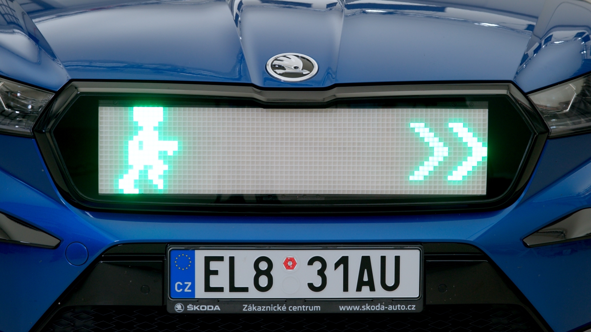 Close up of a Skoda Enyaq grille with LED light system for pedestrians, depicting green man and green arrow