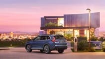 Rear profile of all-new Honda CR-V in blue in front of futuristic property during a purple sunset