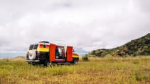 A 1977 Dodge Tradesman camper van wide shot on grassy meadow