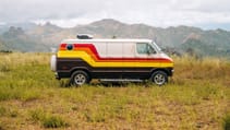 A 1977 Dodge Tradesman camper van side profile shot on grassy meadow