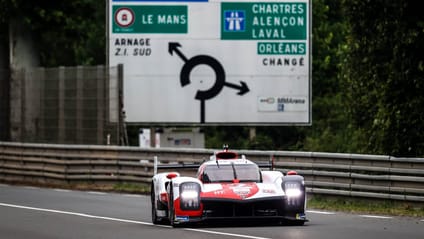 Toyota GR010 Hybrid out on track in front of road sign point to Le Mans