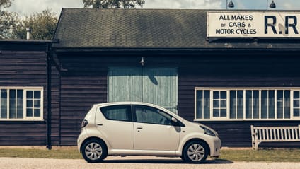 Aygo in side profile shot with old-school garage backdrop