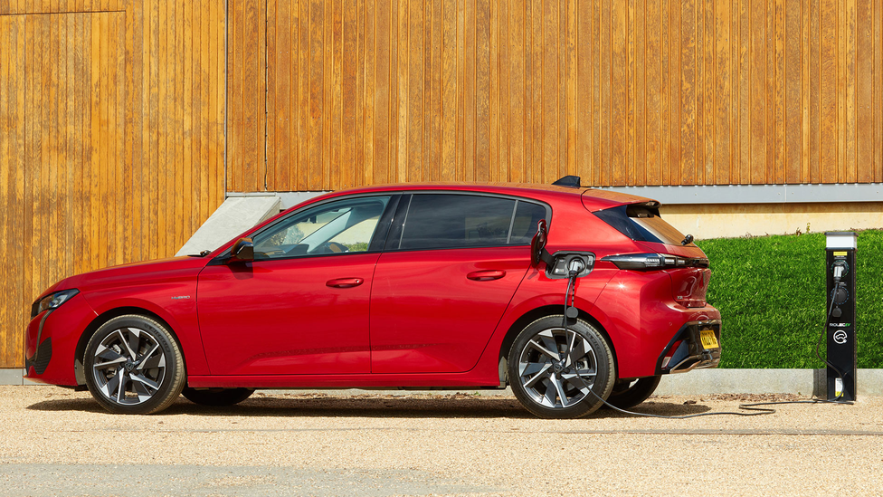 Side profile static shot of Peugeot 308 PHEV plugged into charging point