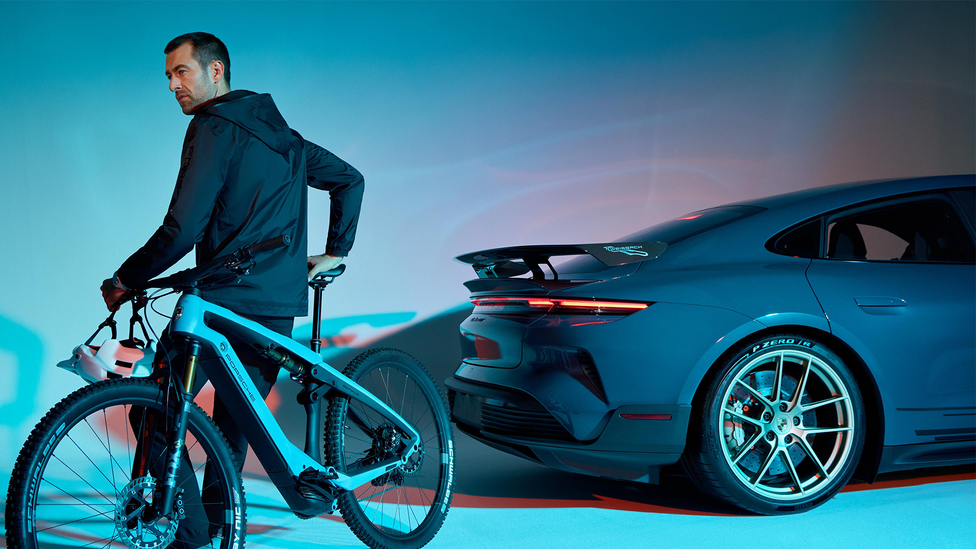 Man leaning on new Porsche eBike in front of Taycan Turbo GT