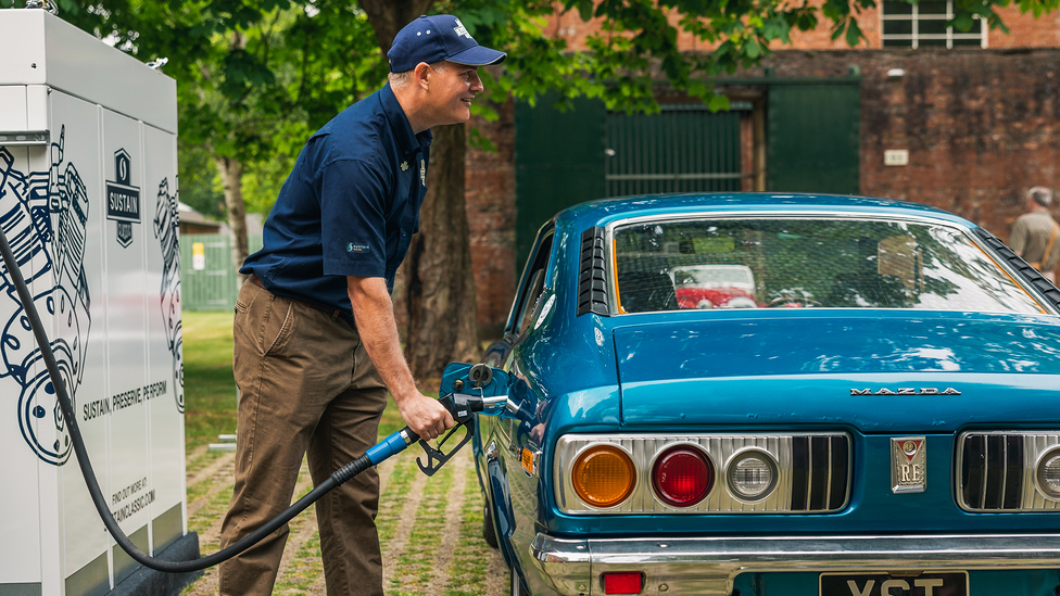 Man refuelling classic Mazda with sustainable fuel