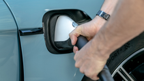 Close up of Porsche Taycan 4S charging port with driver plugging cable in