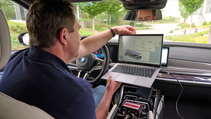 BMW solid-state engineer in interior shot sitting behind steering wheel with laptop open for analysis