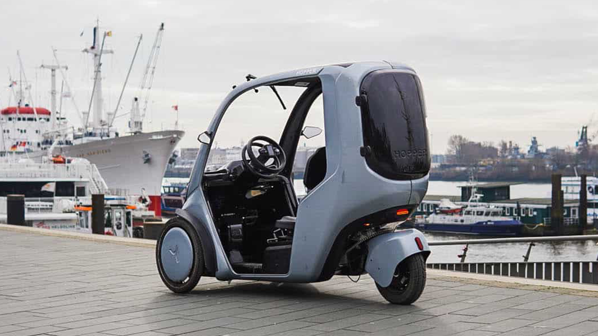 Static shot of the Hopper e-Bike (covered trike) with a harbour backdrop