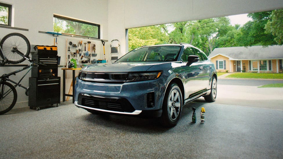 A modern electric car parked in a garage with cleaning products on the ground nearby