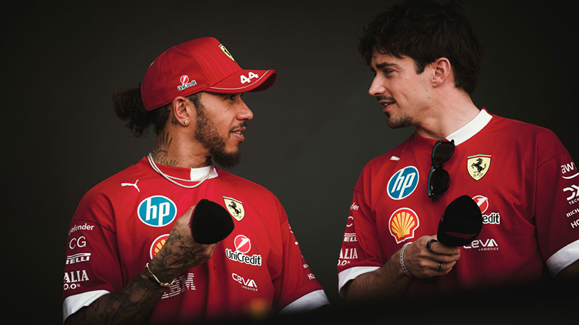 Charles Leclerc and Lewis Hamilton holding mics and chatting during an interview