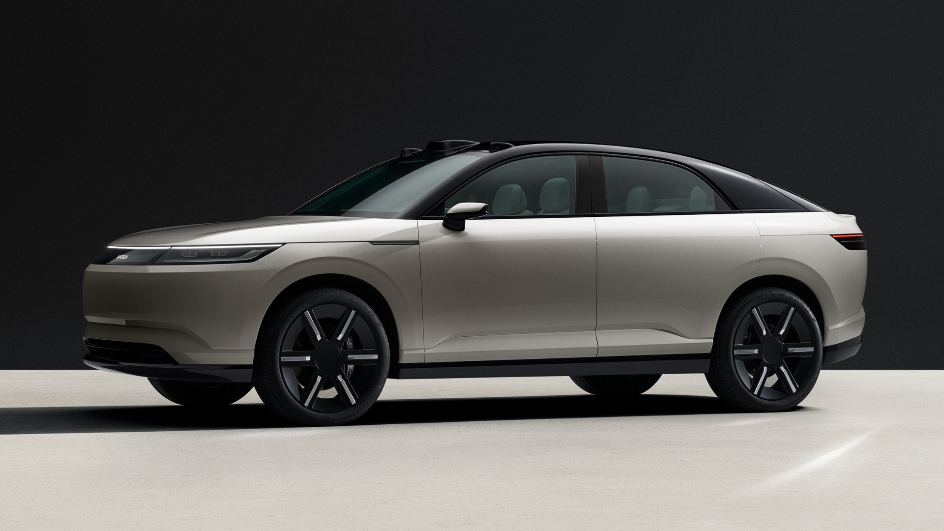 A light-coloured Afeela electric car is parked against a dark background.