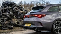 The back half of Cupra Leon Estate VZ1 parked in front a pile of used tyres