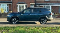 Dacia Bigster parked outside a house, pictured from the side.