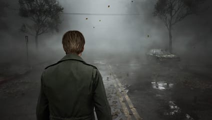 A person stands on a fog-covered road with an abandoned car in the distance.