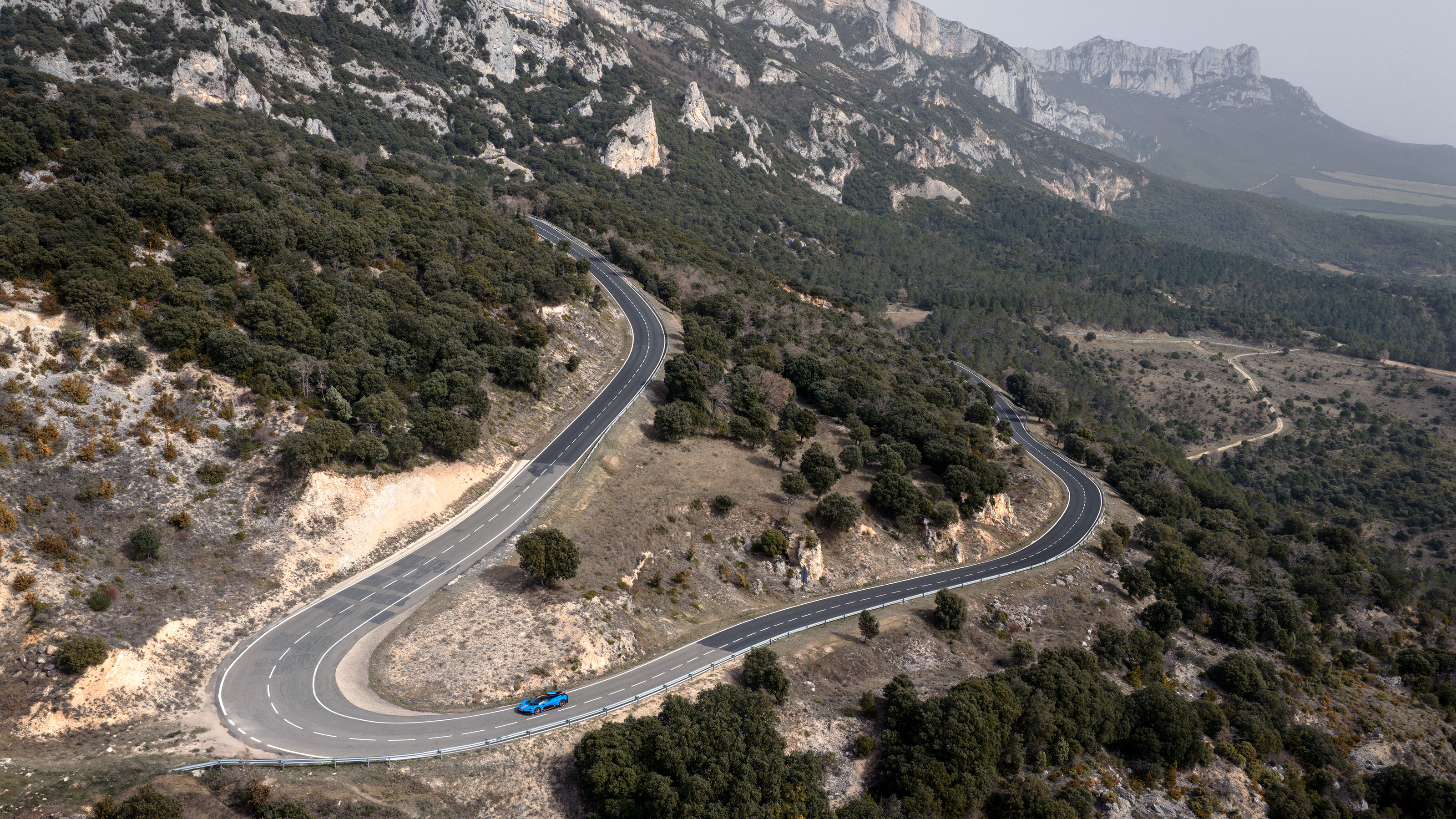 Wide shot of a Aston Martin Valhalla driving on a windy road