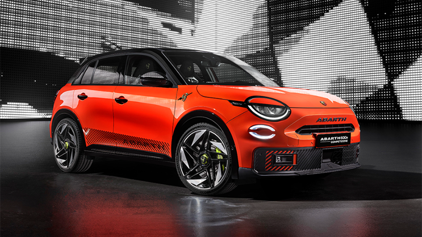 A vibrant orange Abarth electric SUV is showcased with intense lighting, highlighting a modern grille and sleek, sporty design against a futuristic backdrop