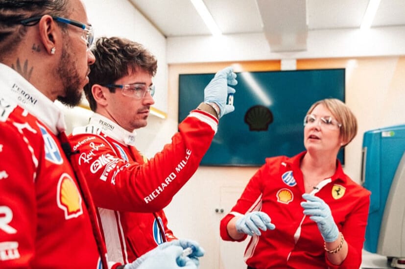 Scuderia Ferrari HP F1 drivers Charles Leclerc and Lewis Hamilton talking to a member of the team in the Shell Track Lab