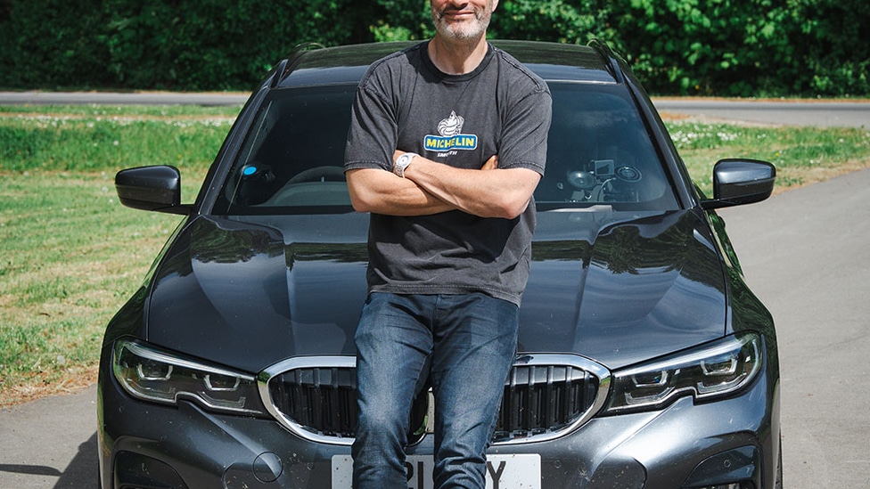 Joe Achilles leaning again the bonnet of a black 2022 BMW 330D Touring