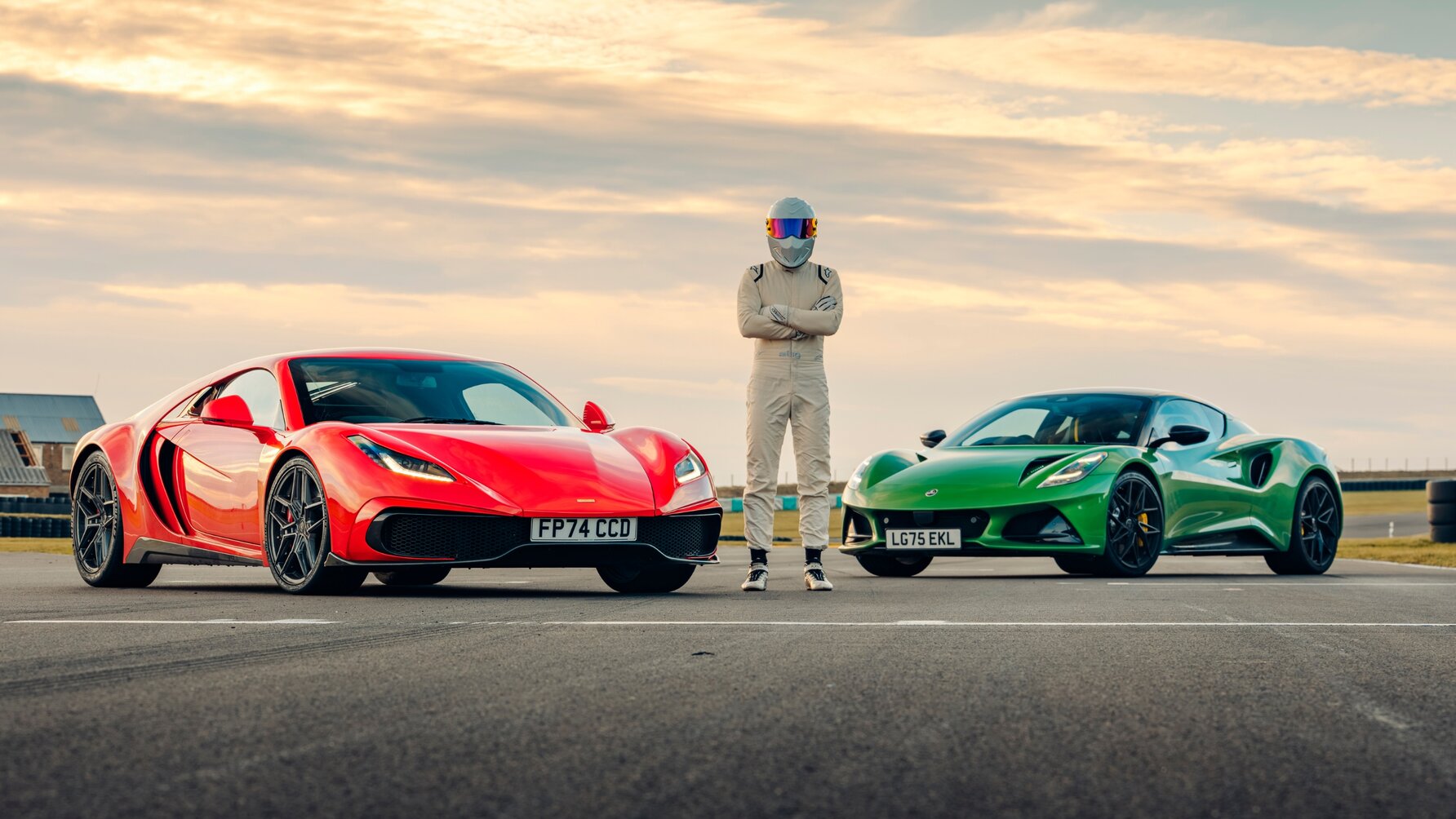 Noble M500 and Lotus Emira parked next to each other, pictured from the front with The Stig standing between them.
